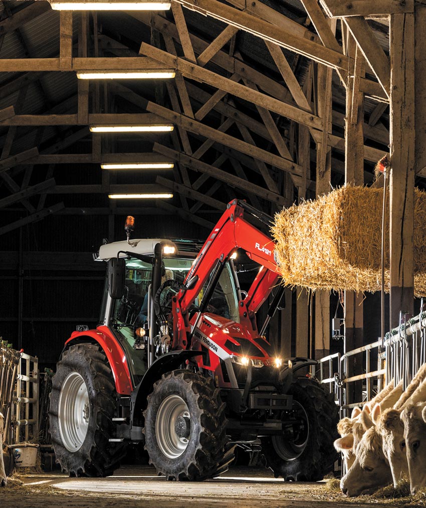 Red Massey Ferguson 5S Series tractor lifting hay bale in barn