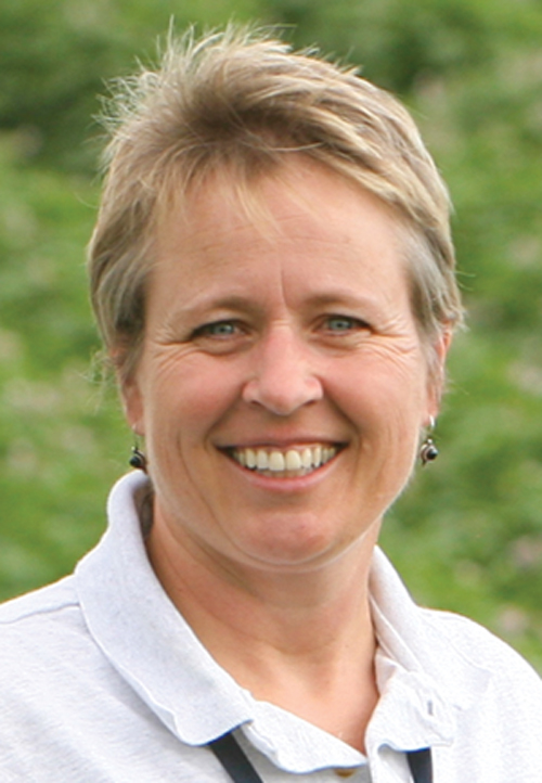 A Headshot of Nina Zidack smiling in a gray collared shirt